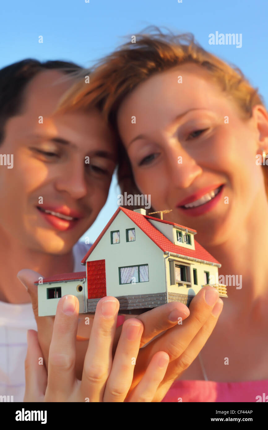 Giovane donna e uomo mantenendo in mani modello di casa con garage Foto Stock
