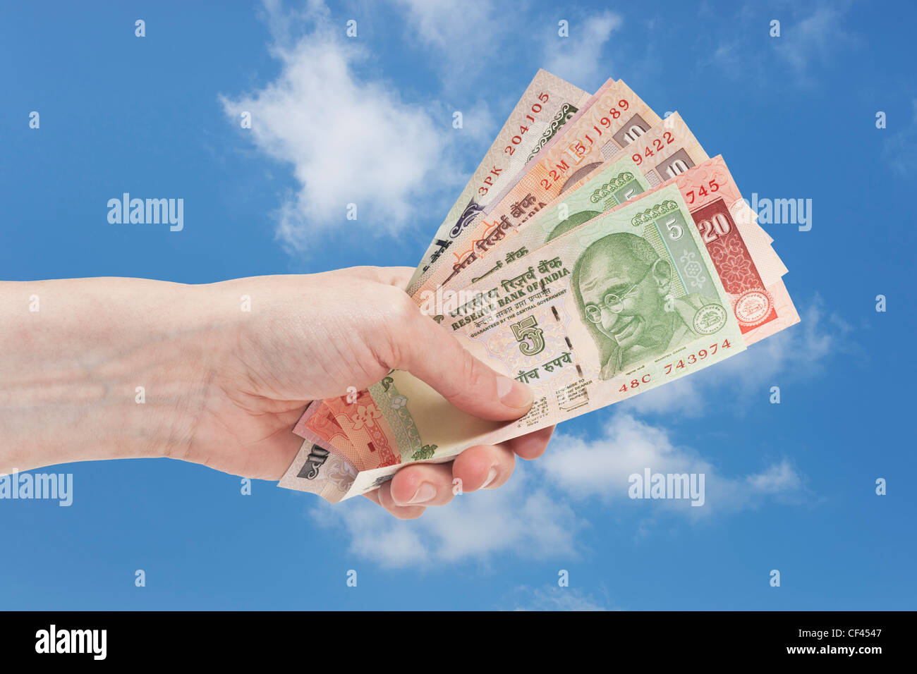 Molti diversi rupia indiana fatture con il ritratto del Mahatma Gandhi sono tenute in mano. Il cielo è in background. Foto Stock