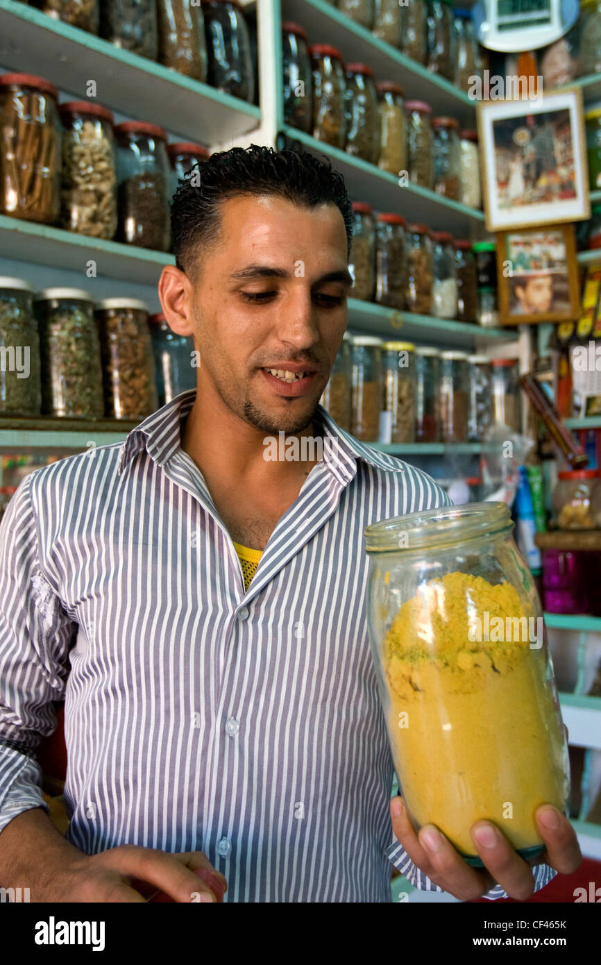 Un locale spice shop proprietario in piedi con un barattolo di spezie nel suo negozio in Djemaa el Fna mercato in Marrakech Marocco Foto Stock