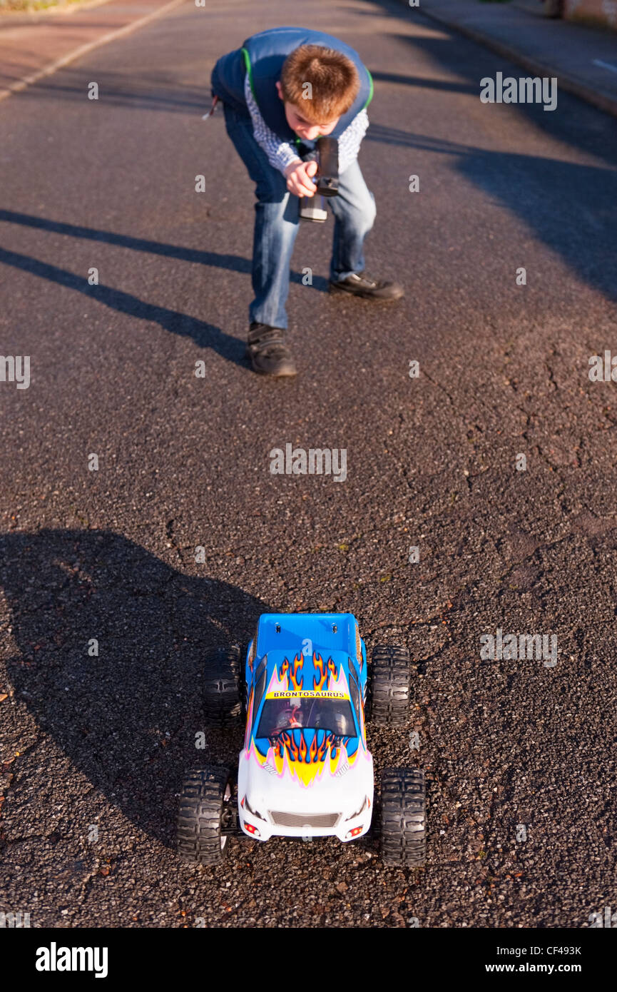 Un dodicenne ragazzo giocando con la sua radio controlled auto in strada in Inghilterra , Inghilterra , Regno Unito Foto Stock