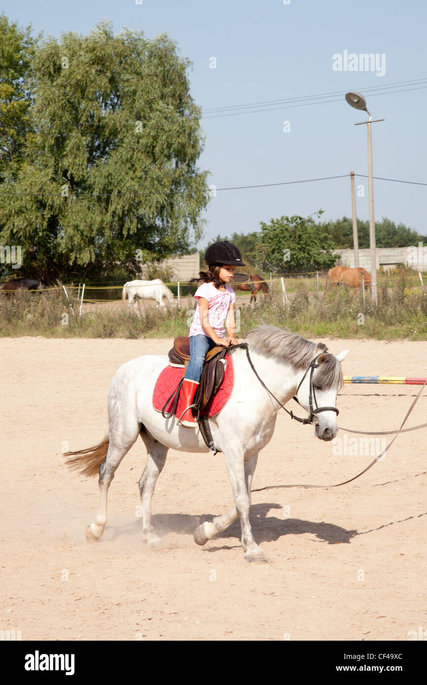 Bambina in sella ad un cavallo e assunzione di equitazione lezioni all'aperto. Foto Stock