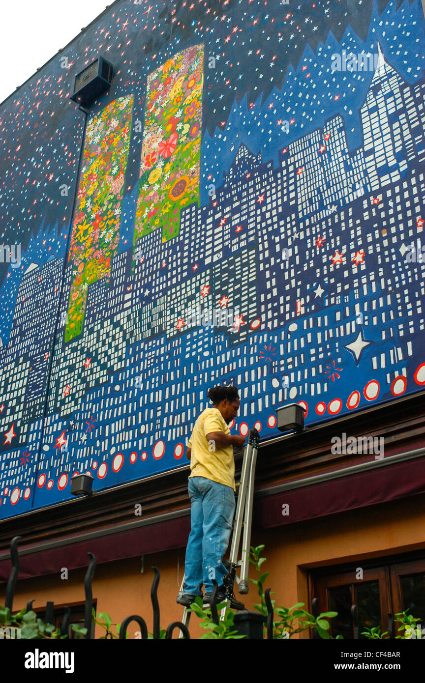 New York City, New York, Stati Uniti, Man on Ladder, Painting Wall Mural on Buiding in East Village, Public Art New york City colorata Foto Stock