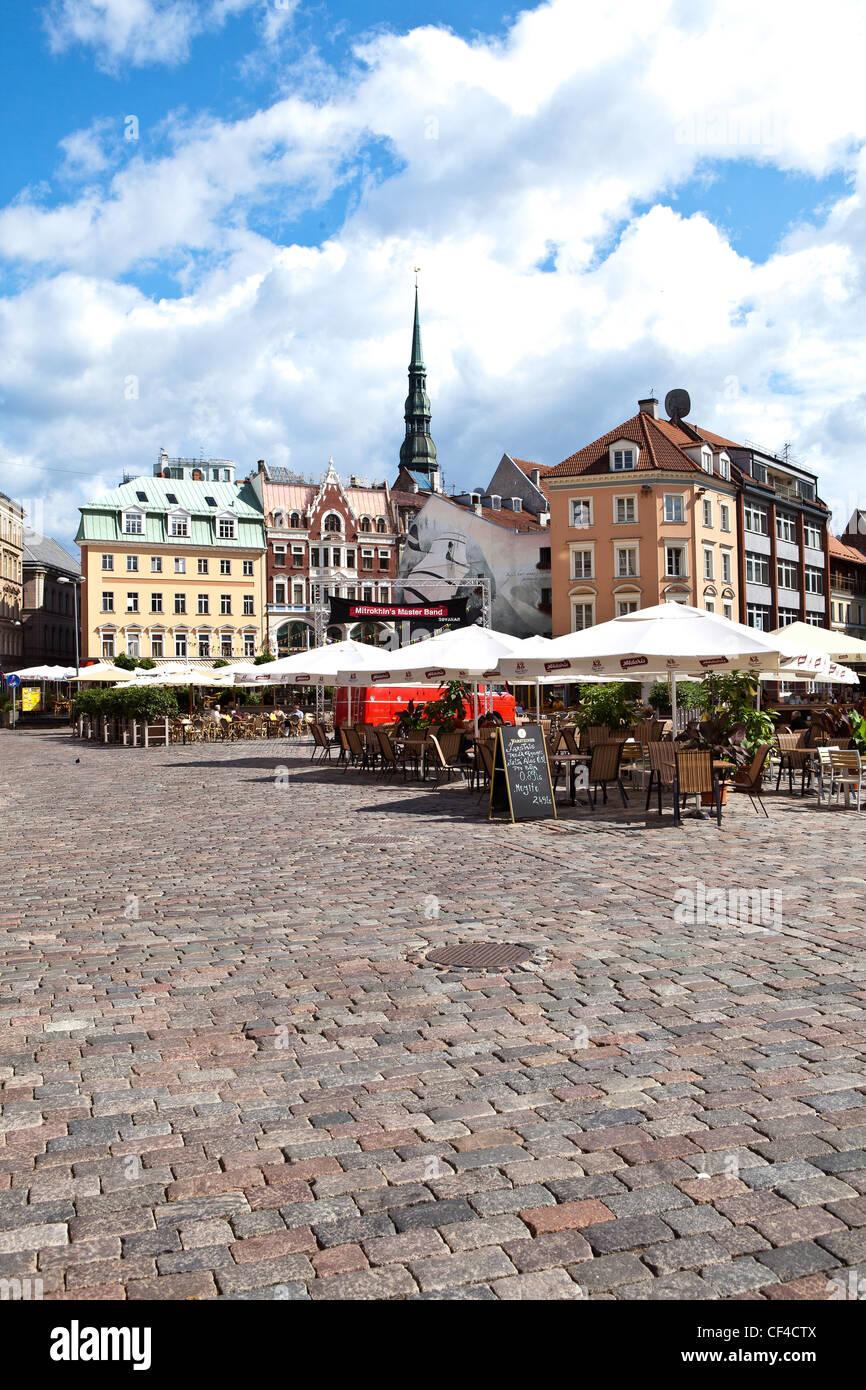 Caffè all'aperto in Piazza Duomo nella città vecchia di Riga con il campanile della chiesa di San Pietro in background. Foto Stock