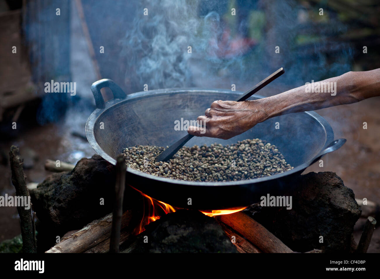 Agitazione a mano i chicchi di caffè sul fuoco; Muara Pinang Indonesia Foto Stock