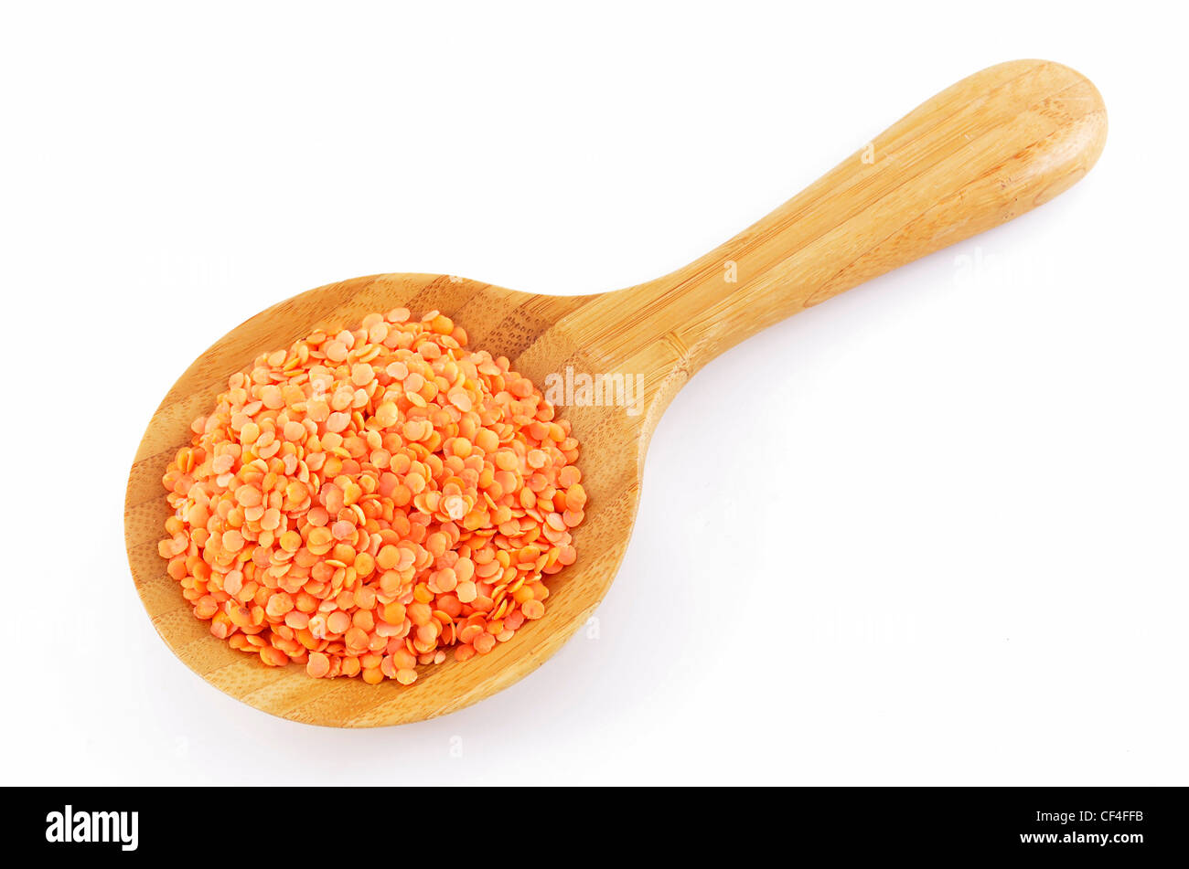 Di lenticchie rosse in cucchiaio di legno su sfondo bianco Foto Stock