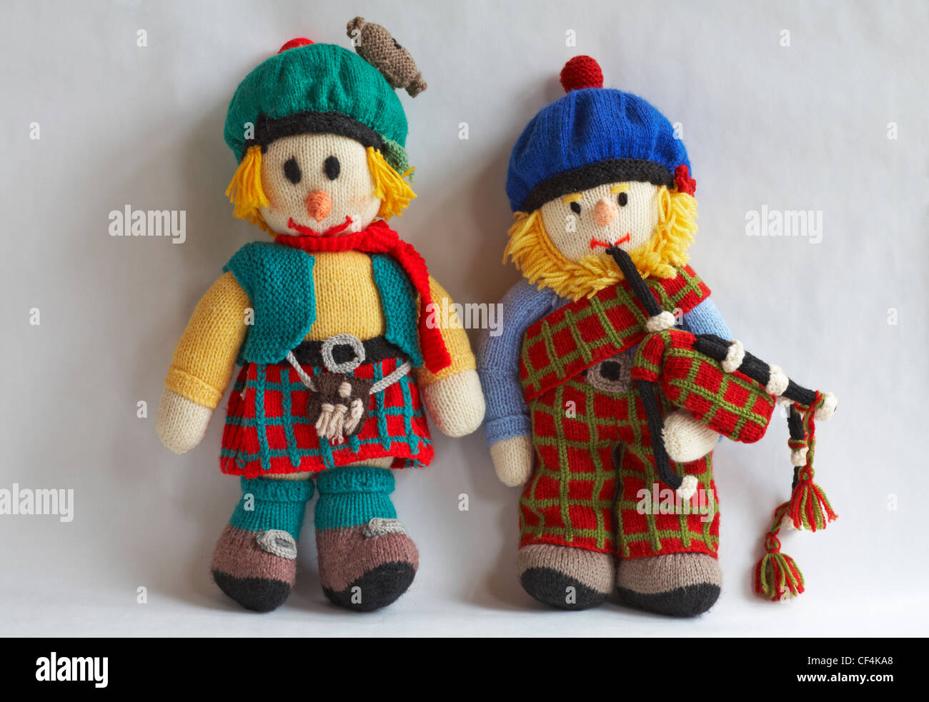 Due bambole scozzesi giocattoli a maglia isolati su sfondo bianco - bambole a maglia, giocattoli a maglia, bambola a maglia, giocattolo a maglia Foto Stock