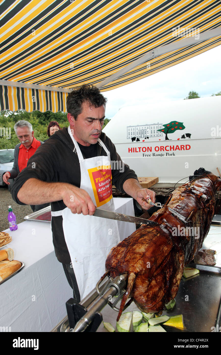 Film del regista Kevin Allen carving un Hilton Orchard arrosto di maiale. Allen corre Flatlake, un letteraria/ Music Festival presso l'Hilton Park, un Foto Stock