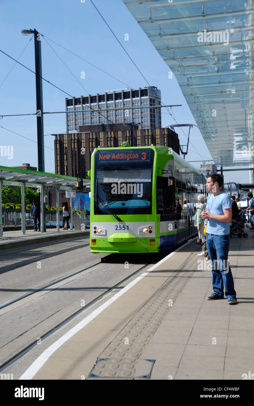 Un uomo in piedi su una piattaforma in attesa di un tram su Croydon Tramlink fuori la stazione ferroviaria di East Croydon. Foto Stock