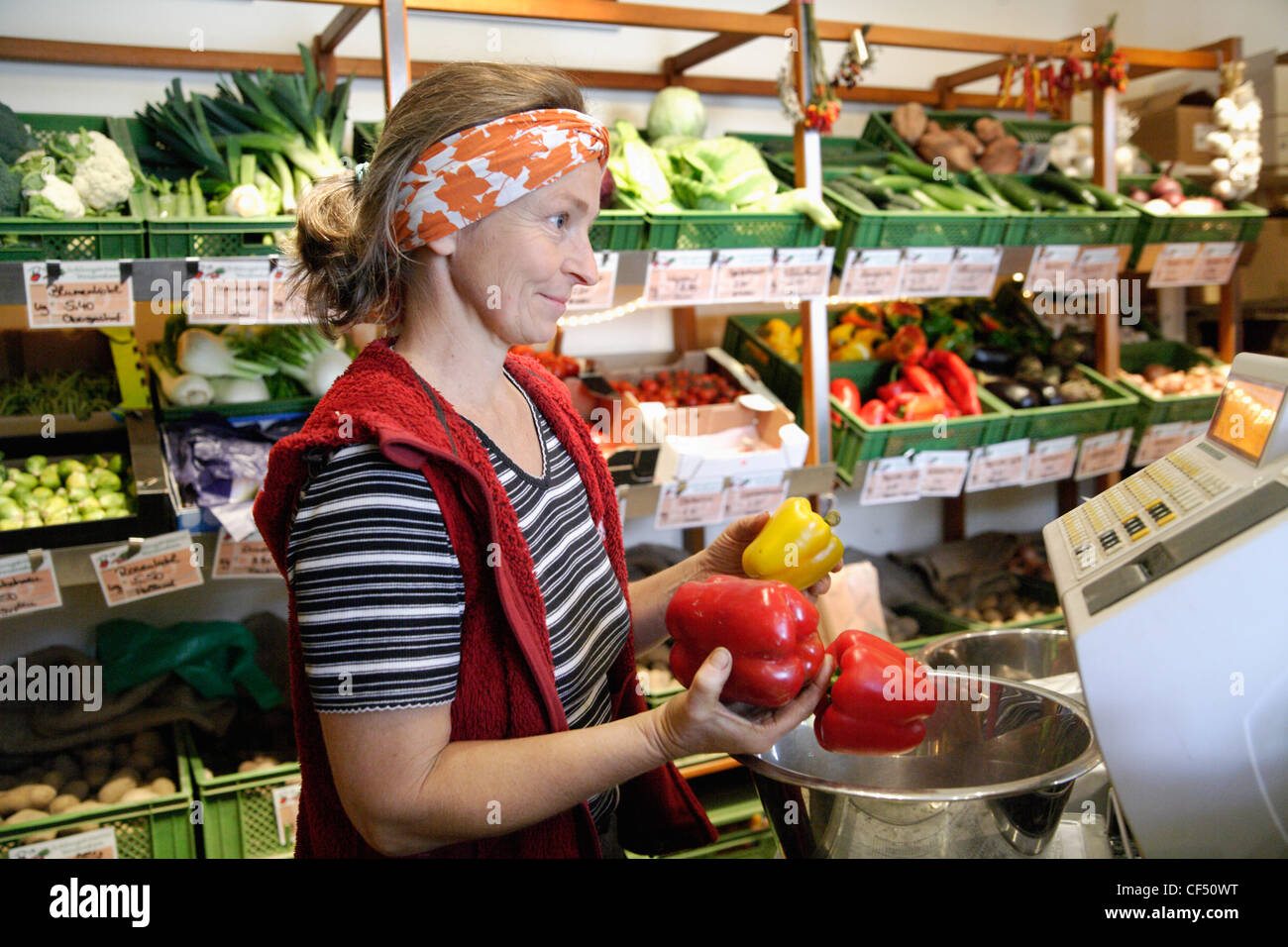 In Germania, in Baviera, Wolfratshausen donna matura con il rosso e il giallo dei peperoni in negozio Foto Stock