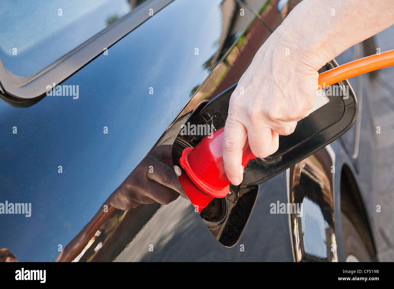 Germania, donna matura la ricarica auto elettrica con cavo di alimentazione Foto Stock