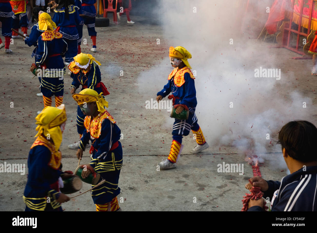 Ragazzi Thai in carattere cinese costume in compagnia di ballo con petardi che esplodono a livello locale tempio Tailandia Bangkok Asia Asian Foto Stock