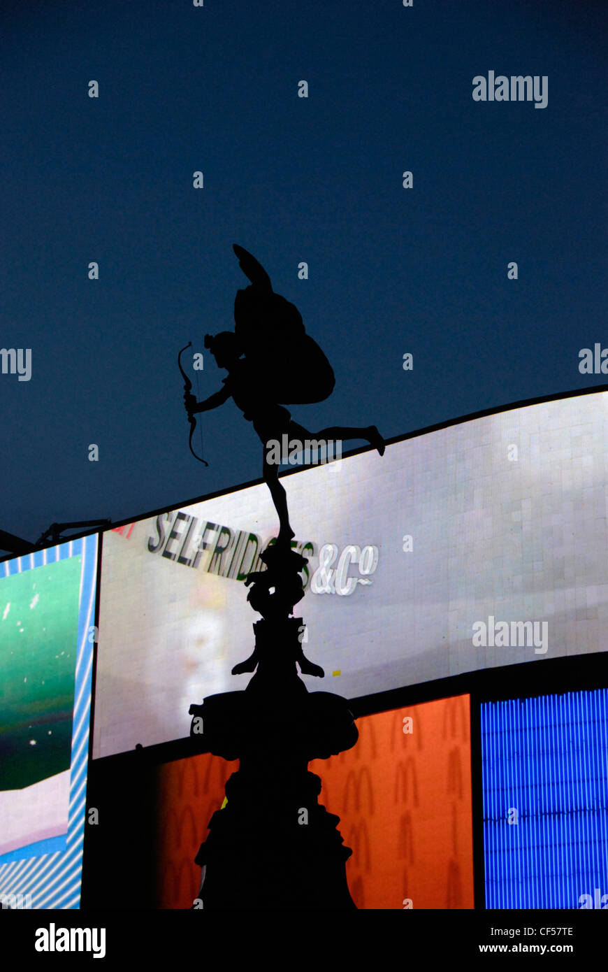 Una silhouette della statua di Eros contro la pubblicità al neon di Piccadilly Circus. Foto Stock