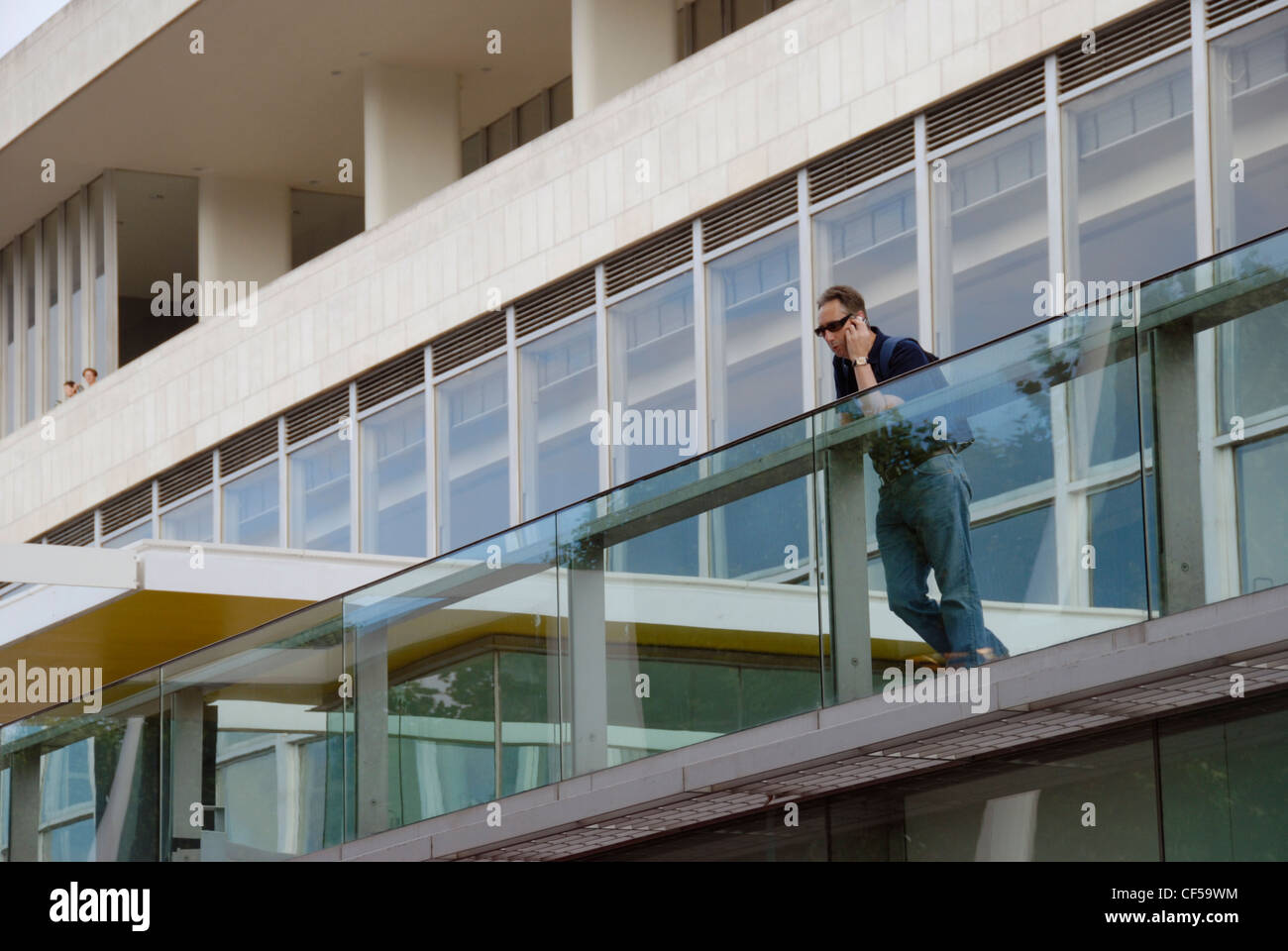 Un uomo che parla per il suo telefono cellulare al di fuori del Royal Festival Hall a South Bank. Foto Stock