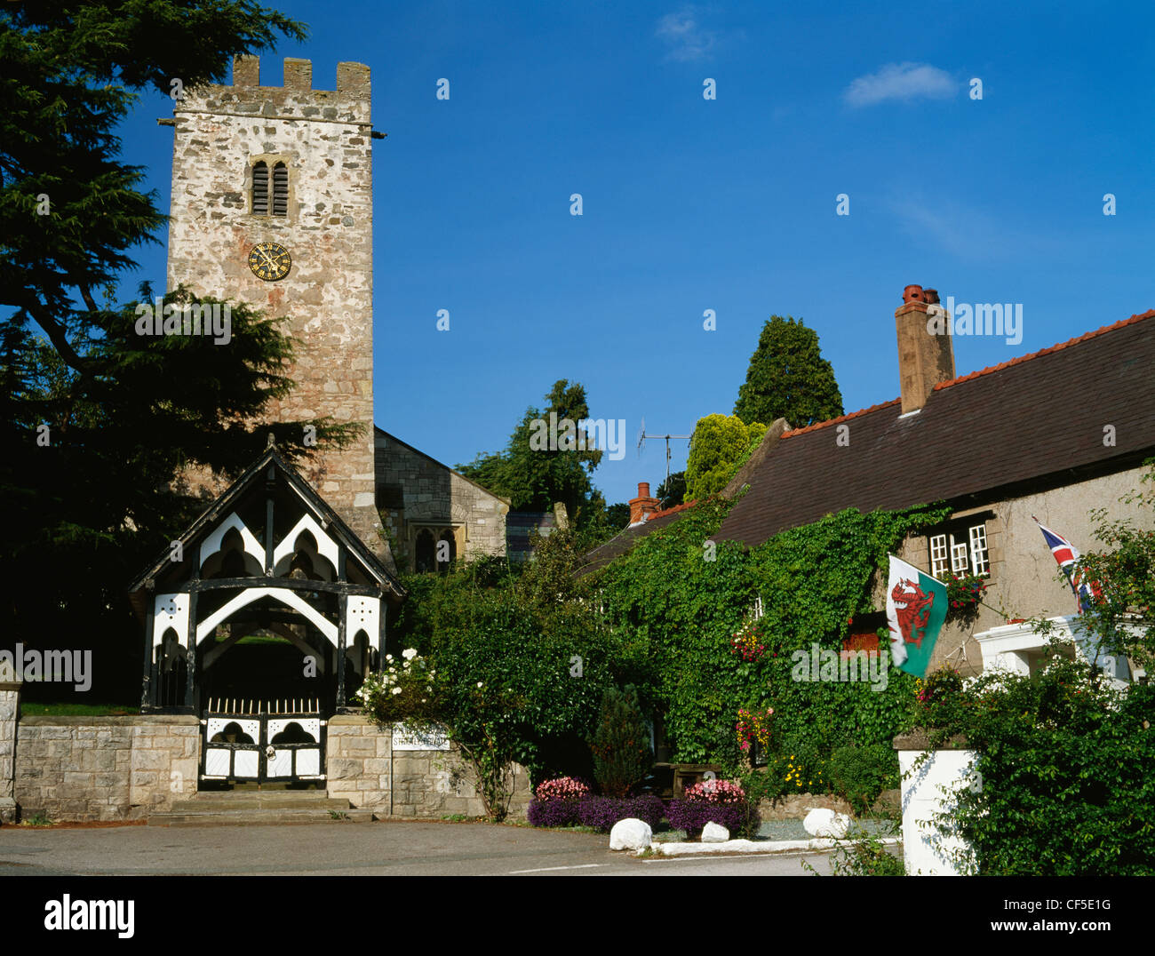 St Stephen's Chiesa e la Dinorben Arms Hotel battenti gallese e il Regno Unito le bandiere nazionali. Foto Stock