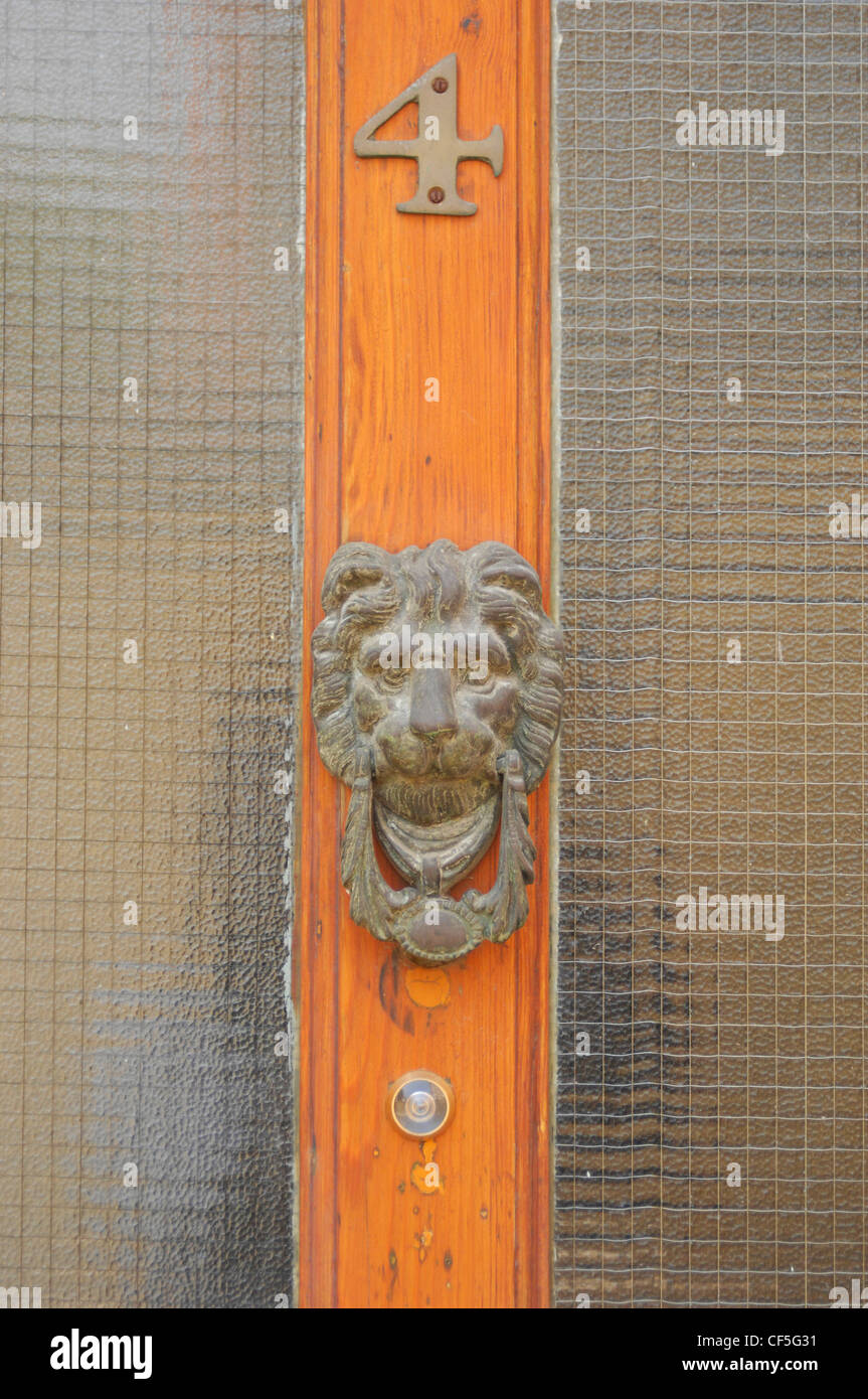 Il legno e il vetro anteriore del pannello dowith un leone in ottone a forma di testa respingente Foto Stock