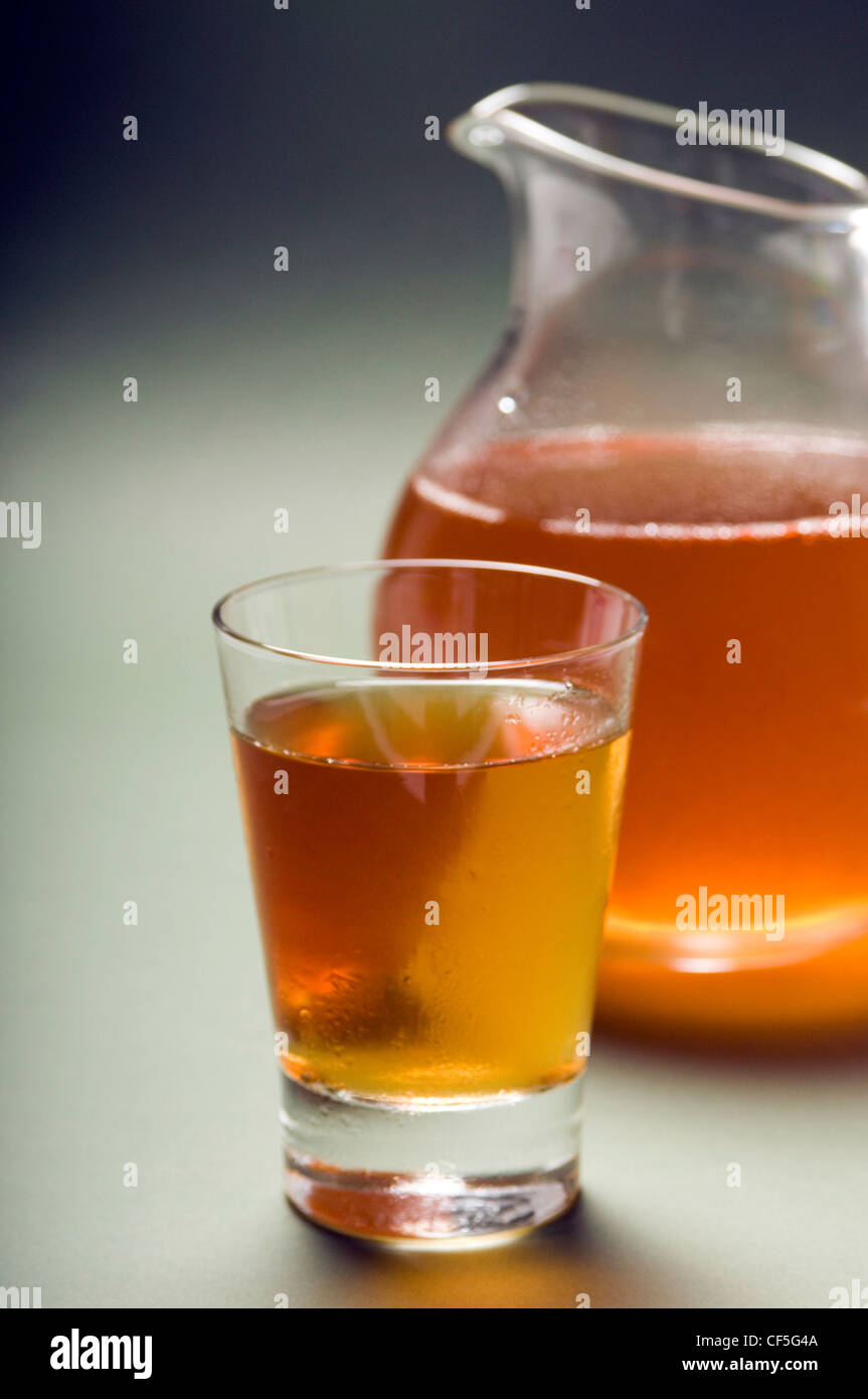 Una brocca e un bicchiere di succo di mela su sfondo verde Foto Stock
