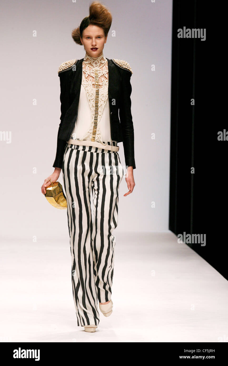 Top bianco pizzo e oro dettaglio sul petto e giacca nera impreziosito  spalle, bianco e nero a strisce larghe pantaloni zampe Foto stock - Alamy