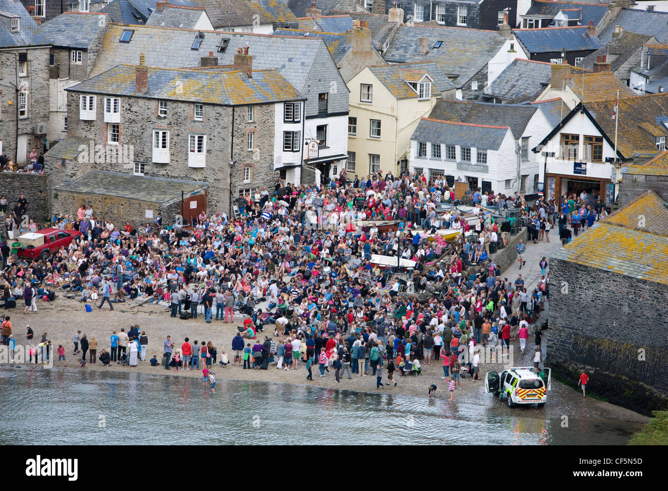 La folla in Port Isaac, Cornwall, guardando il Fisherman's amici shanty cantanti sulla spiaggia Foto Stock
