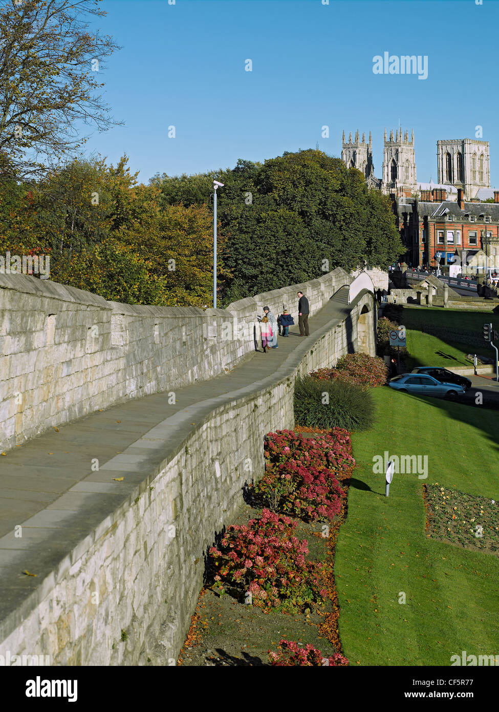 Una famiglia a piedi lungo le mura della città verso York Minster. Foto Stock