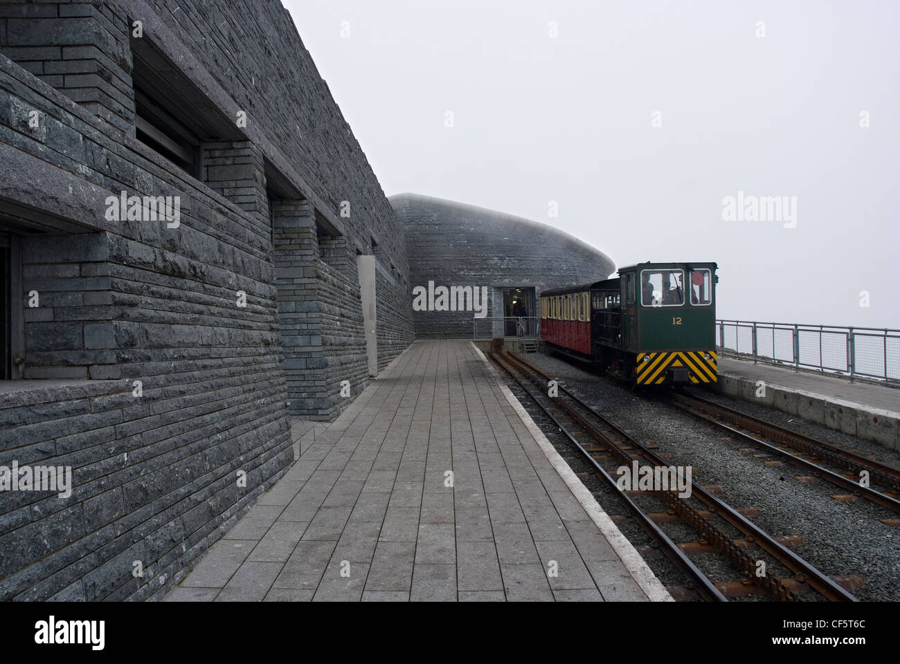 Un treno sulla ferrovia di Snowdon Mountain accanto alla piattaforma al di fuori del nuovo Snowdon centro visitatori al vertice. Foto Stock