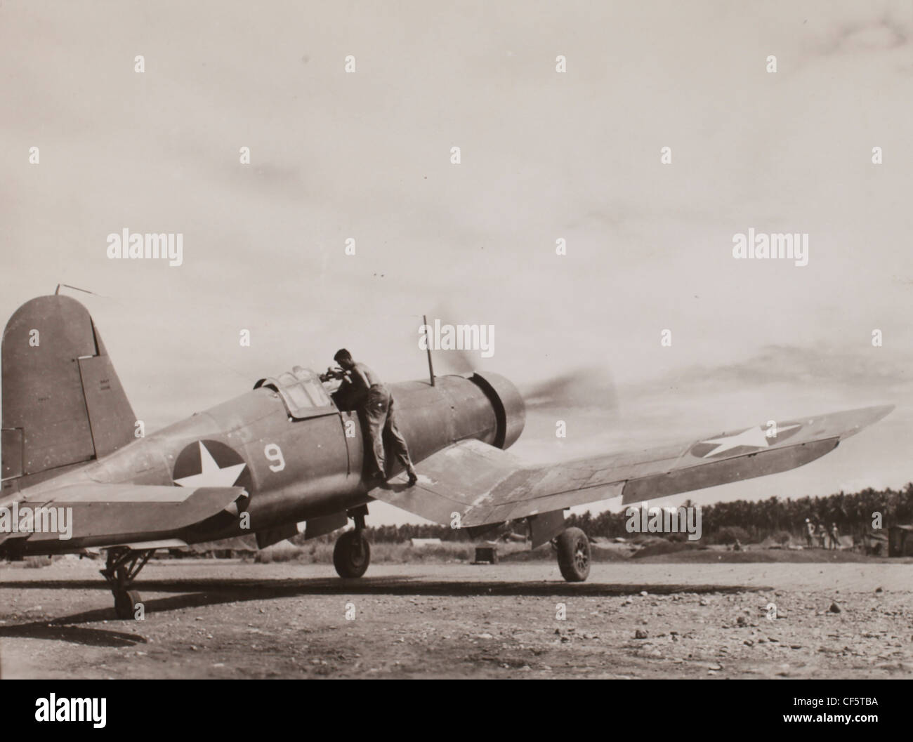 US Marine Corps WWII Pacific Campagna: un pilota si arrampica nel cockpit del suo piano il meccanico aiuta a lui sullo scivolo. Guadalc Foto Stock