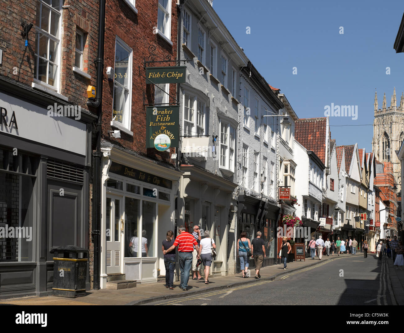 Negozi e ristoranti a bassa Petergate e la West Tower of York Minster. Foto Stock