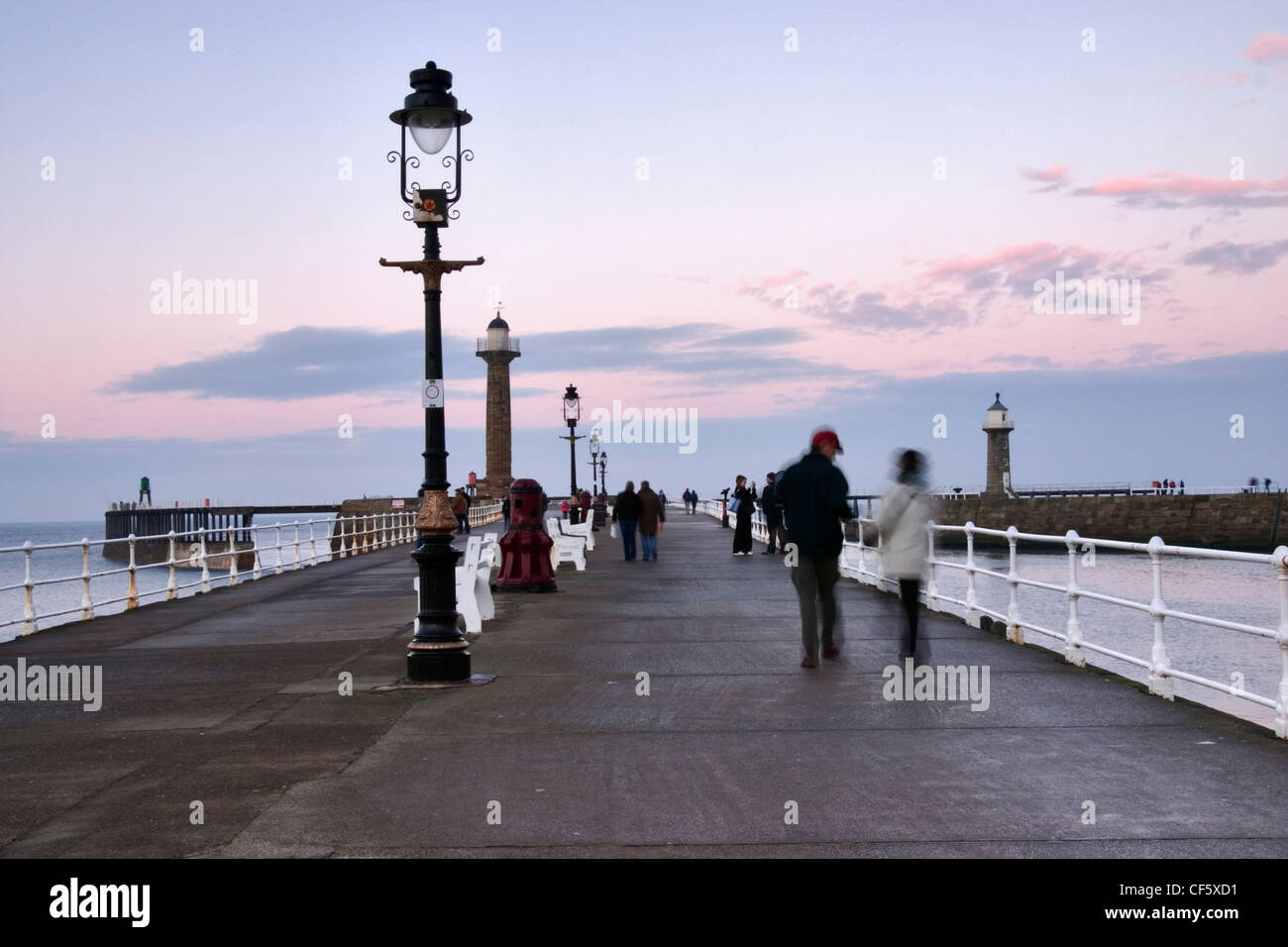 La gente sul molo di Whitby al tramonto. Una grande porzione di Bram Stoker il famoso romanzo è stato impostato a Whitby, descrivendo Dracula io arrivo Foto Stock