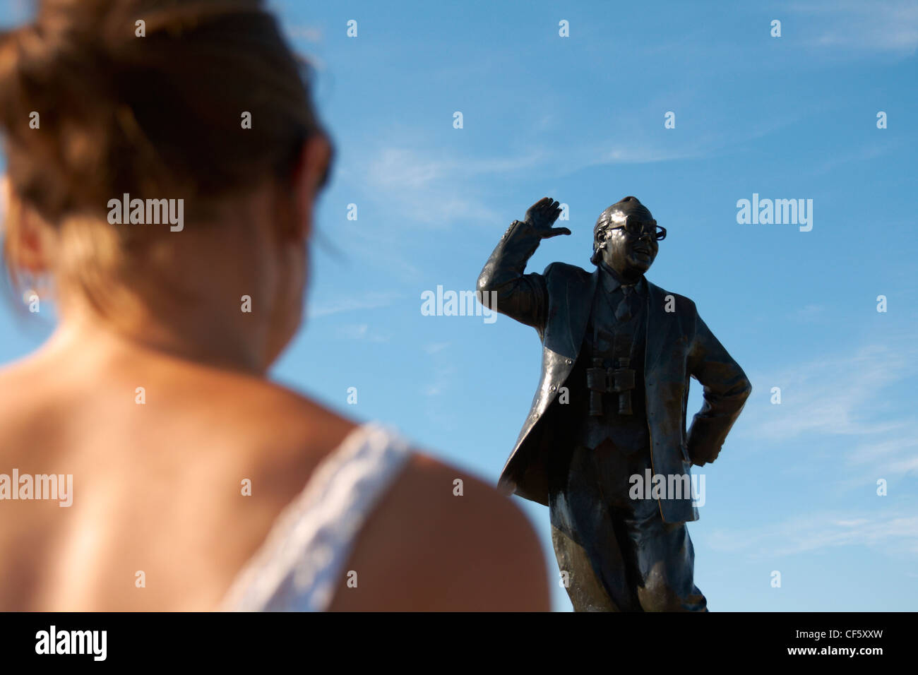 Una donna che guarda la statua di Eric Morecambe su Morecambe fronte mare. Foto Stock
