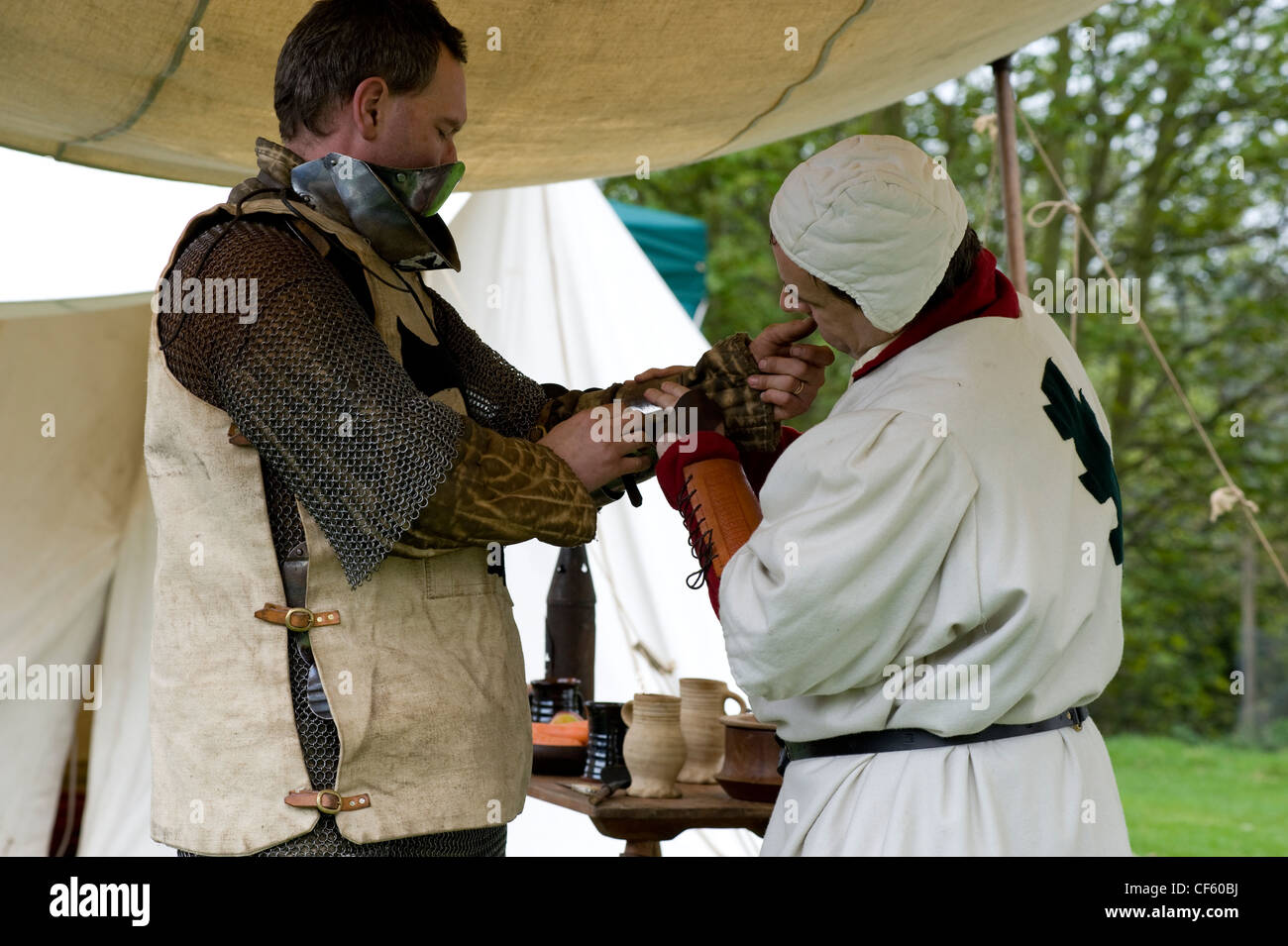 Un cavaliere di essere preparati per la battaglia in un medievale rievocazione presso il Castello di Hedingham. Foto Stock