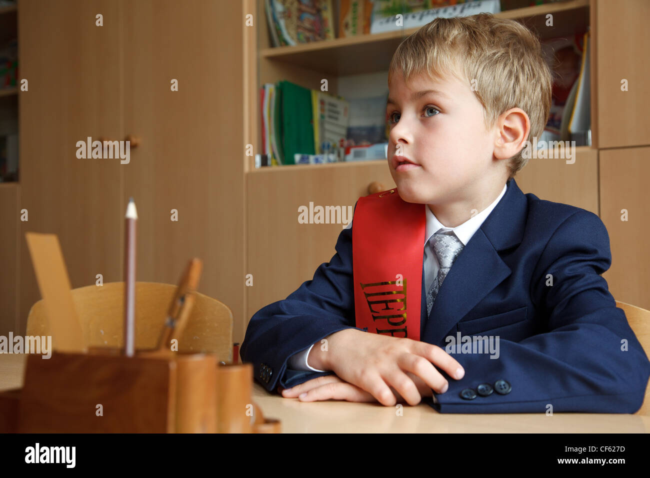 Di prima classe. Ragazzo in uniforme scolastica alla sua scrivania. Foto Stock