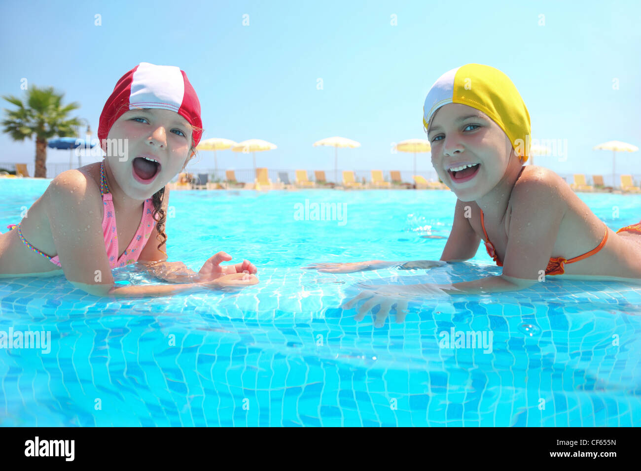 Due ragazze si trovano in piscina sul battiscopa e ridere Foto Stock