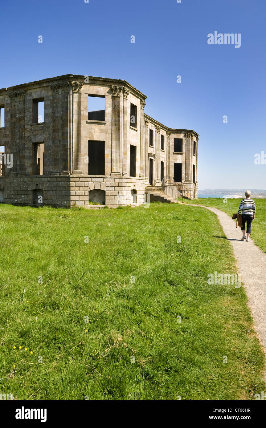 Una donna a piedi lungo un sentiero che conduce ai resti della casa in discesa. Foto Stock