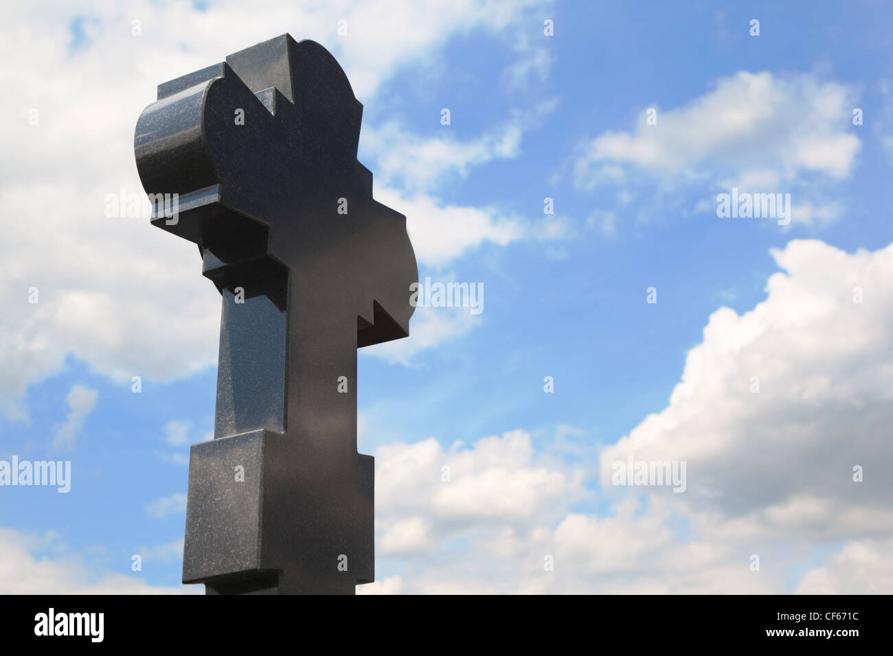 Il granito nero croce sul cimitero, cielo blu con nuvole Foto Stock