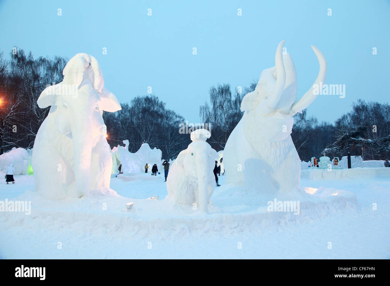 La gente a piedi e sono fotografati contro sculture di neve di elefanti Foto Stock