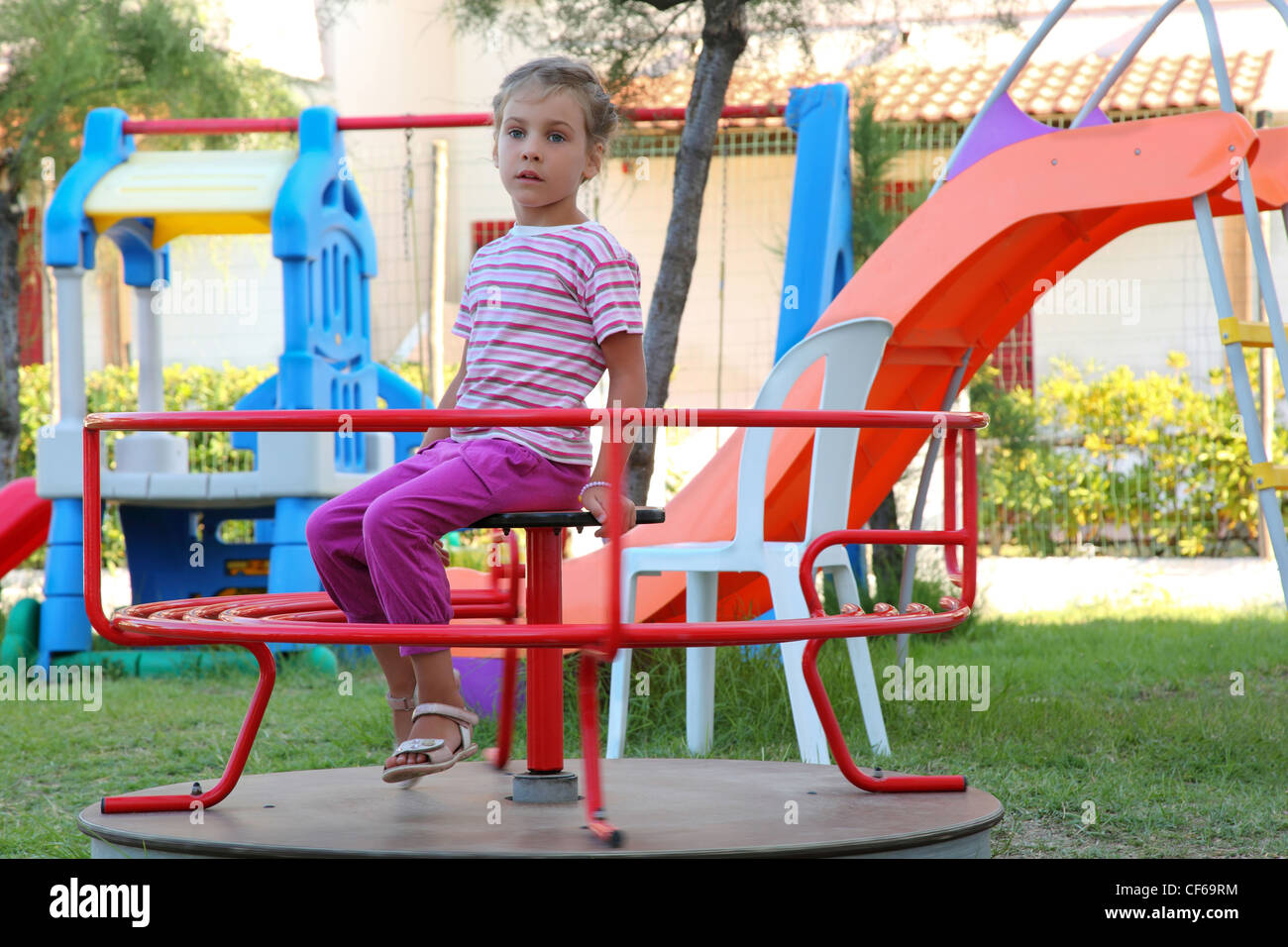 Ragazza va per guidare su merry go-attorno al bambino il suolo Foto Stock