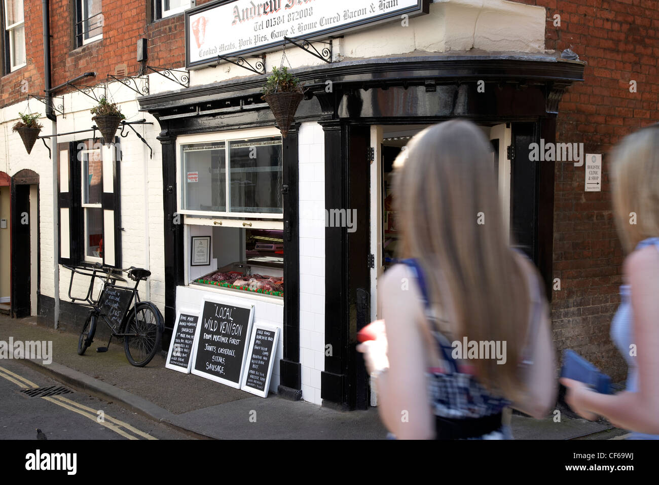 La gente camminare passato il macellaio locale a Ludlow. Foto Stock