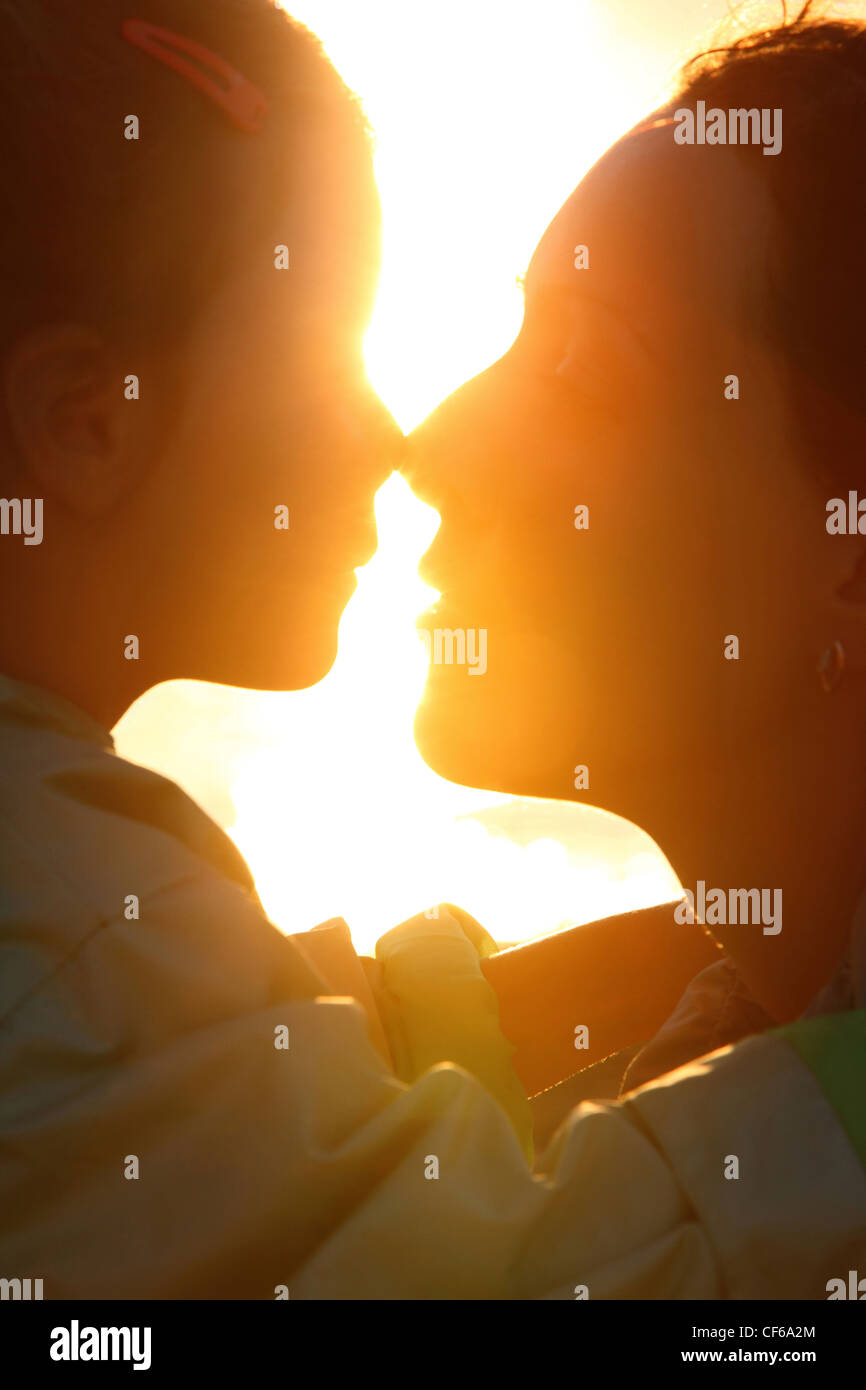 Madre e figlia porfiles in riva al mare a fronte sun toccando dal naso Foto Stock