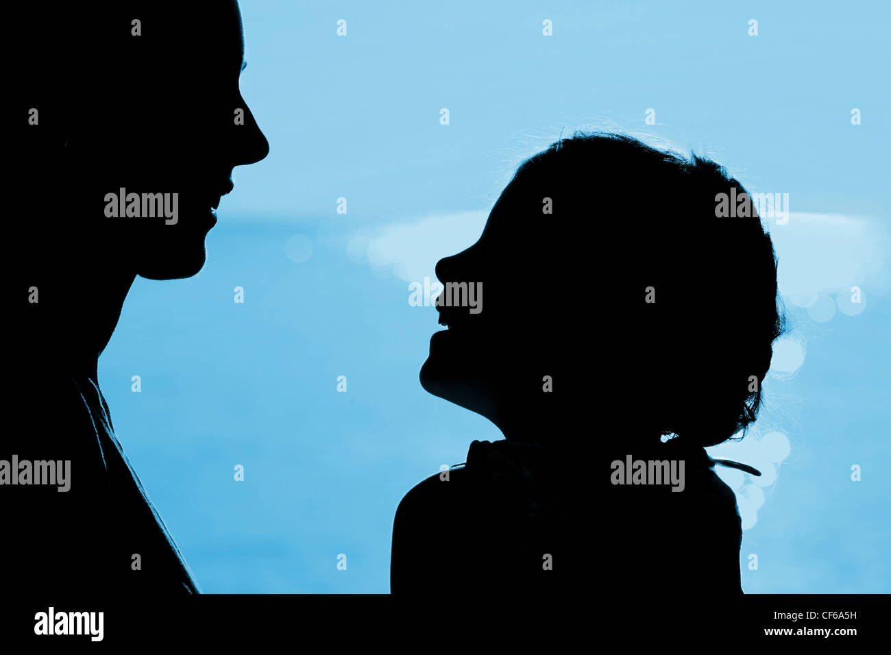 Madre e figlia silhouette vicino al mare, contrapposti, ridendo Foto Stock