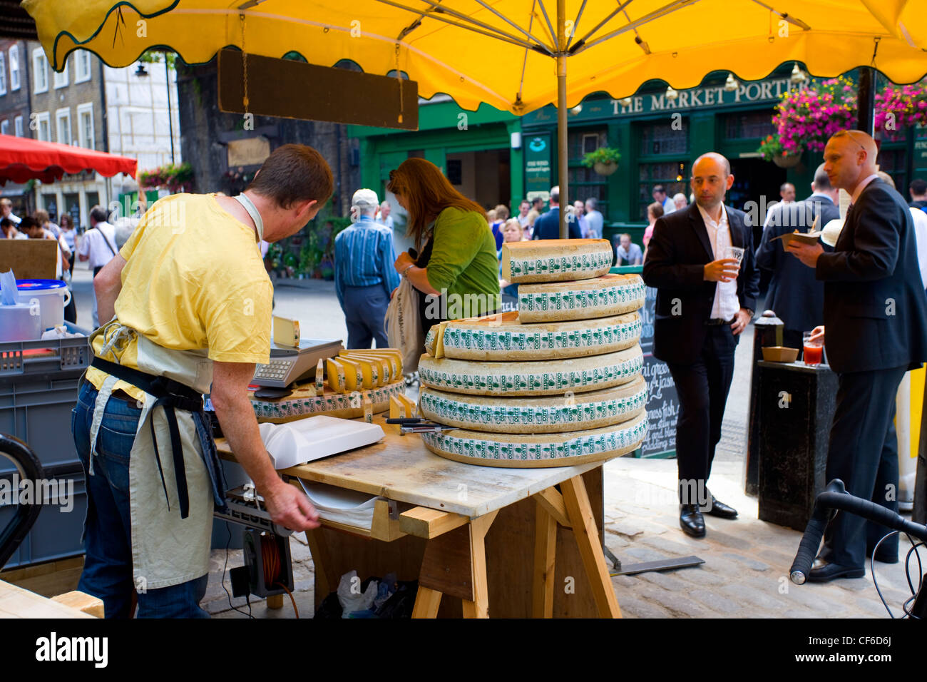Un operatore di mercato la vendita di formaggio dal round di Borough Market. Foto Stock