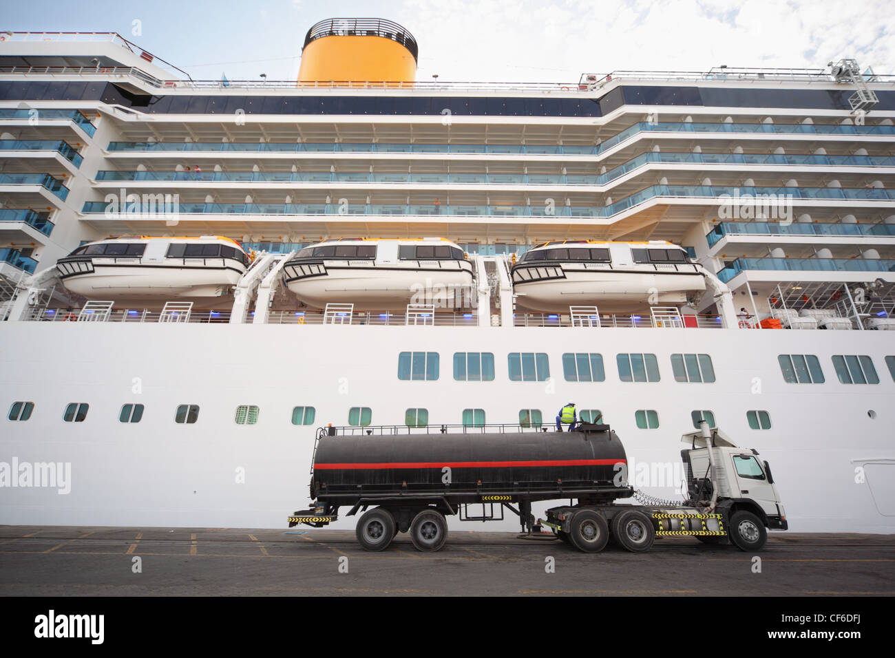 Gas-autobotte soggiornando in Qaboos Port. La nave di crociera dietro il carrello. l uomo sulla parte superiore del carrello. Foto Stock