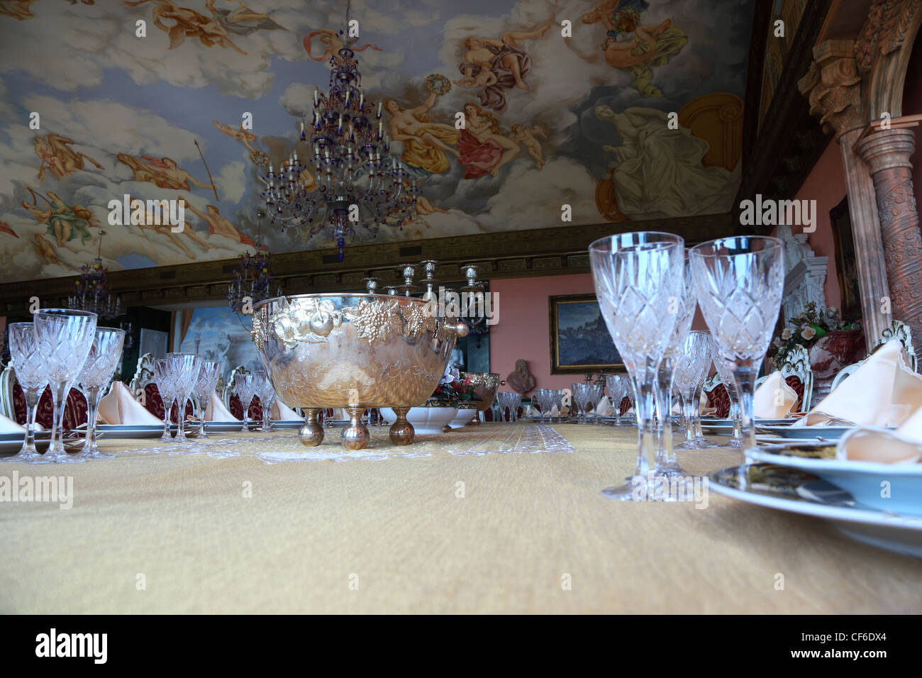 Il rame in centro di grande ovale tavolo per la cena tra piatti vuoti: piastre con placemat, forchette, coltelli e calici Foto Stock