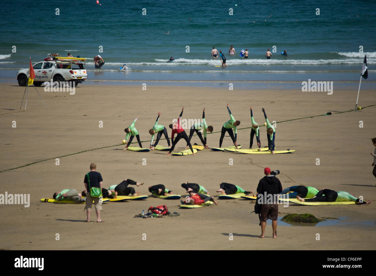 Surfers in fase di riscaldamento sulla spiaggia presso una scuola di surf a Towan Beach, Newquay. Foto Stock