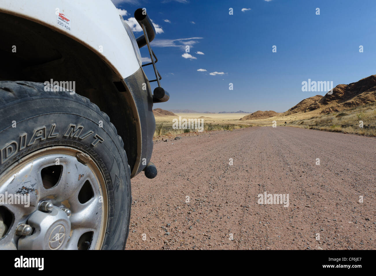 Vista su una strada di ghiaia nel deserto del Namib dalla ruota anteriore di un veicolo a 4 ruote motrici. Namibia Foto Stock