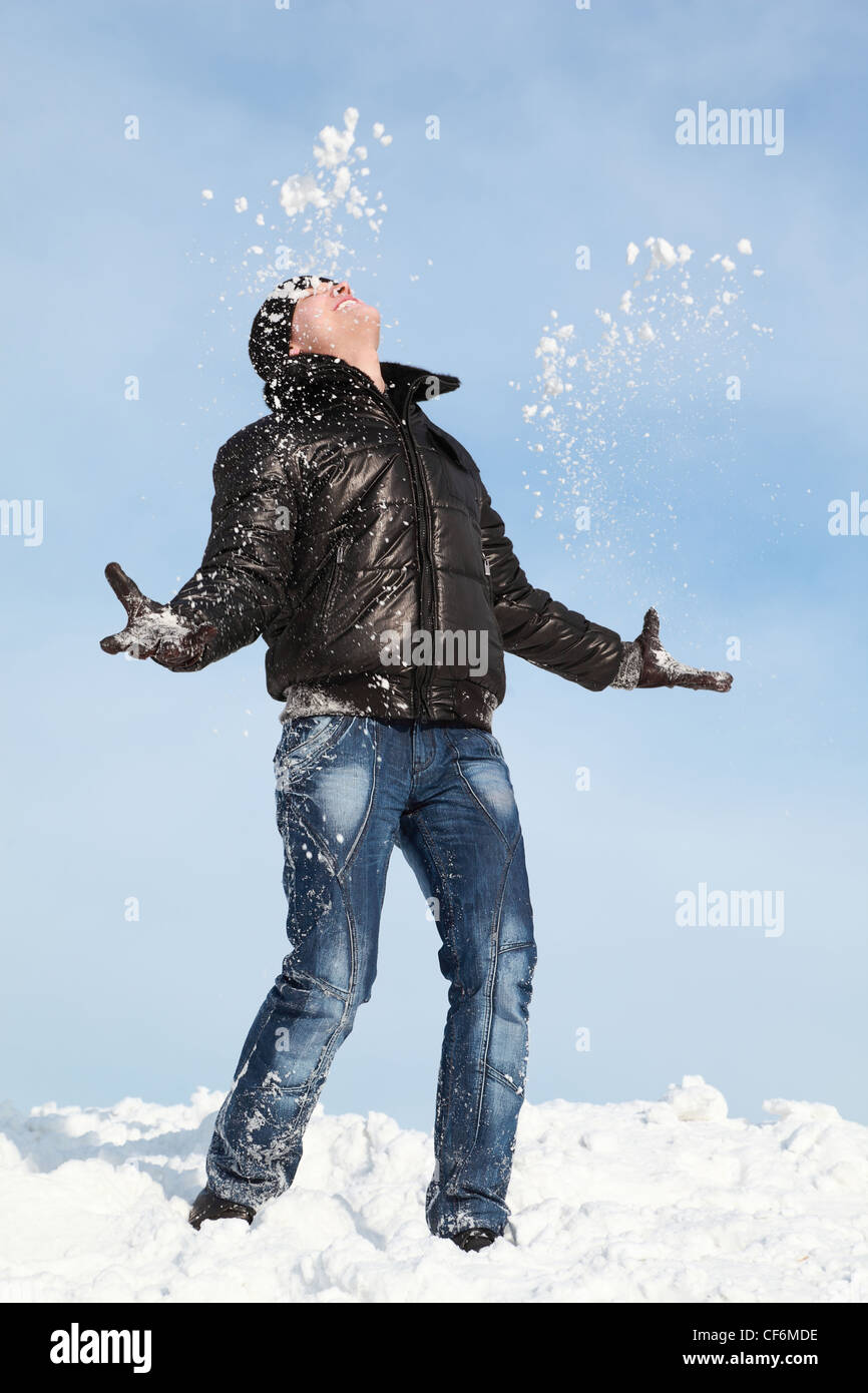 L uomo sta sulla neve di gettare le mani di lui e si guarda in cielo Foto Stock