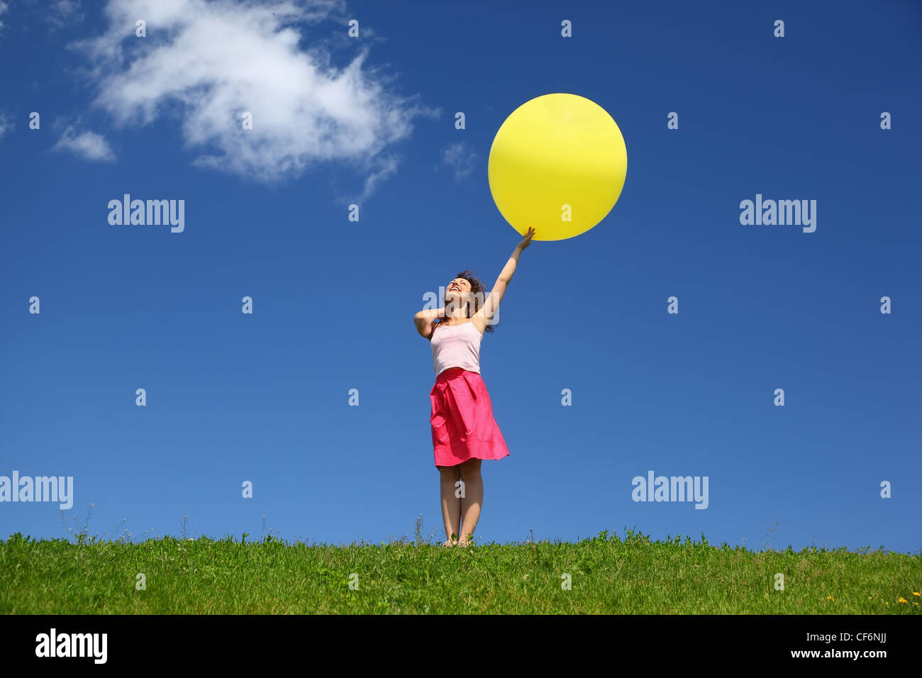 La donna si trova in estate nel campo detiene il palloncino e guarda in cielo Foto Stock