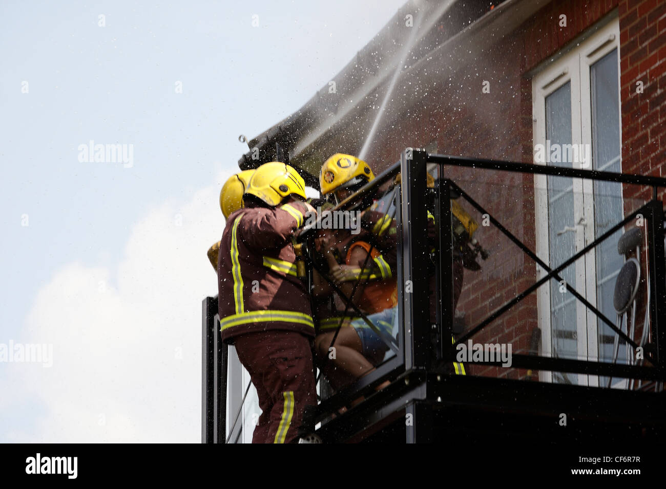 I vigili del fuoco fanno un drammatico salvataggio da un balcone come fuoco rip attraverso il tetto sopra di loro Foto Stock