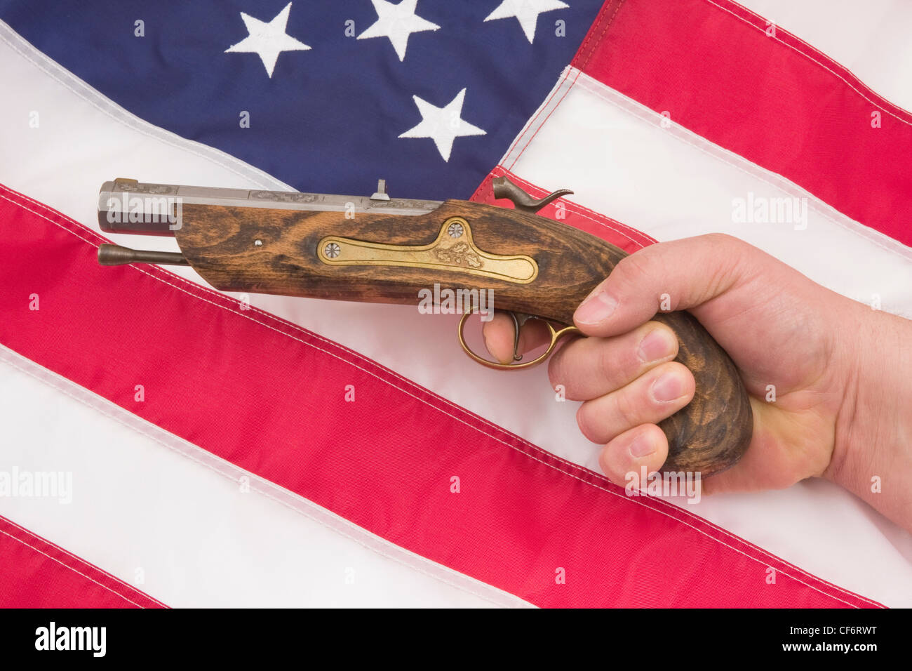 Mano umana tiro pistola antichi sulla bandiera americana sfondo. Foto Stock