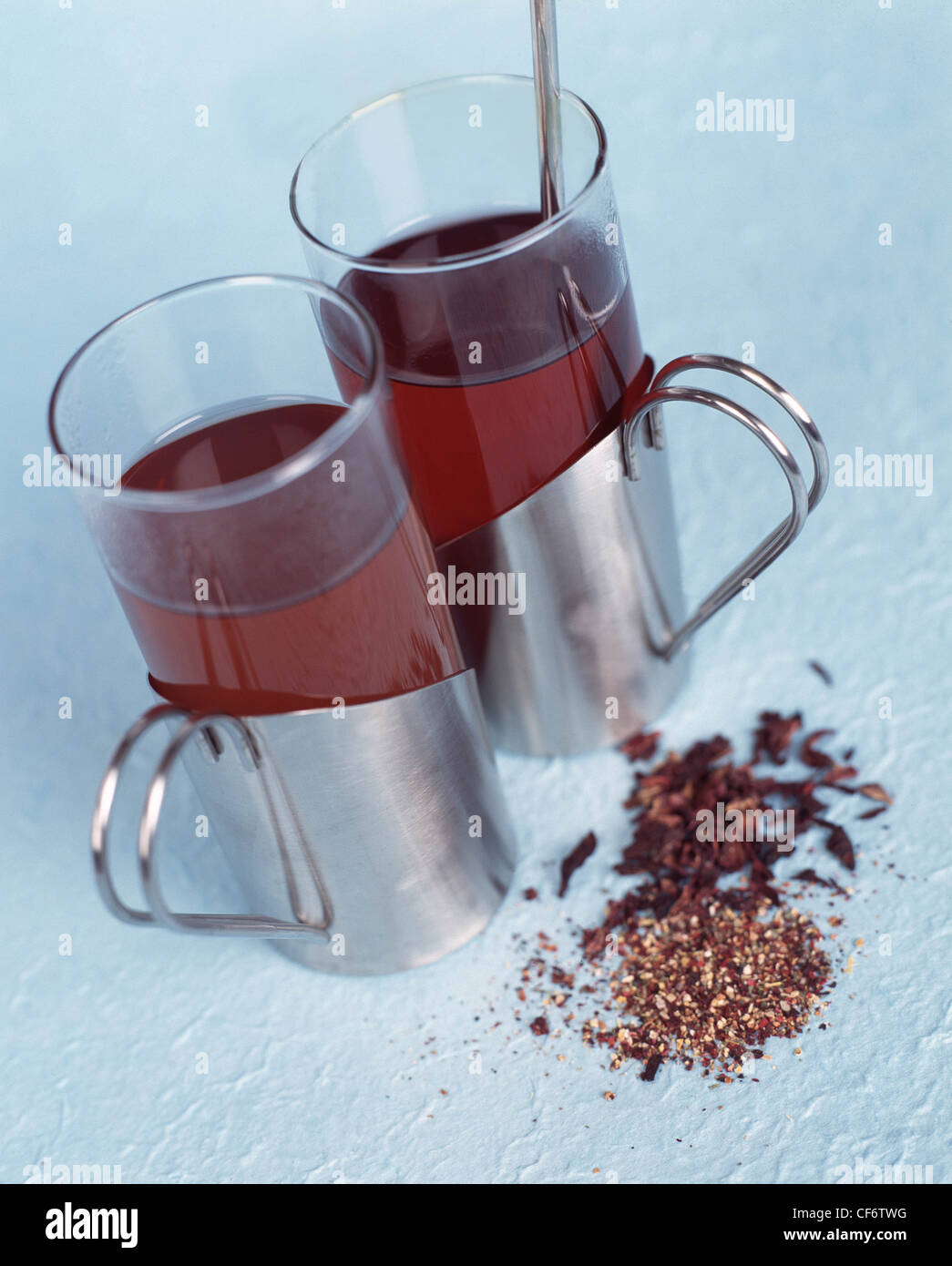 Due coppe d'argento con bicchieri di tè alle erbe con tè alle erbe foglie in primo piano cucchiaio d'argento in una delle coppe Foto Stock
