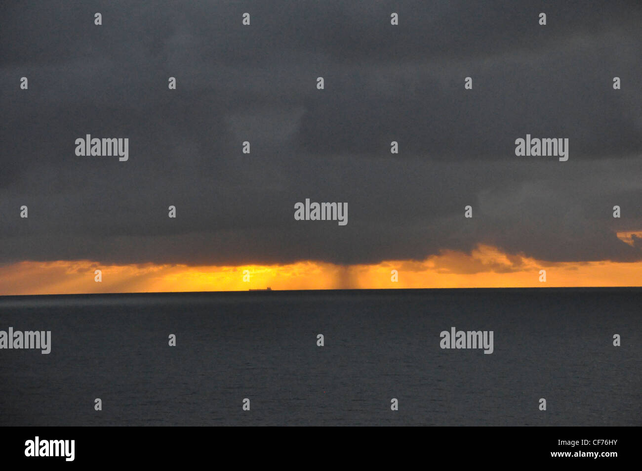 Mar nero cielo nero luce dorata distante pioggia tropicale Foto Stock