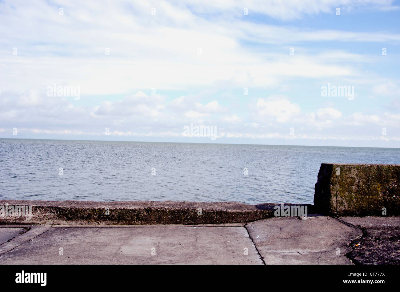 Il vecchio molo di cemento per navi e acqua di mare sky sullo sfondo di un paesaggio. Foto Stock